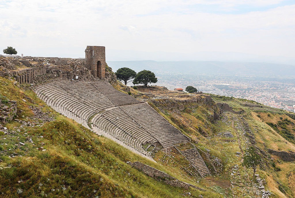 A Steep hillside with stone seating towers above an old orchestra circle.