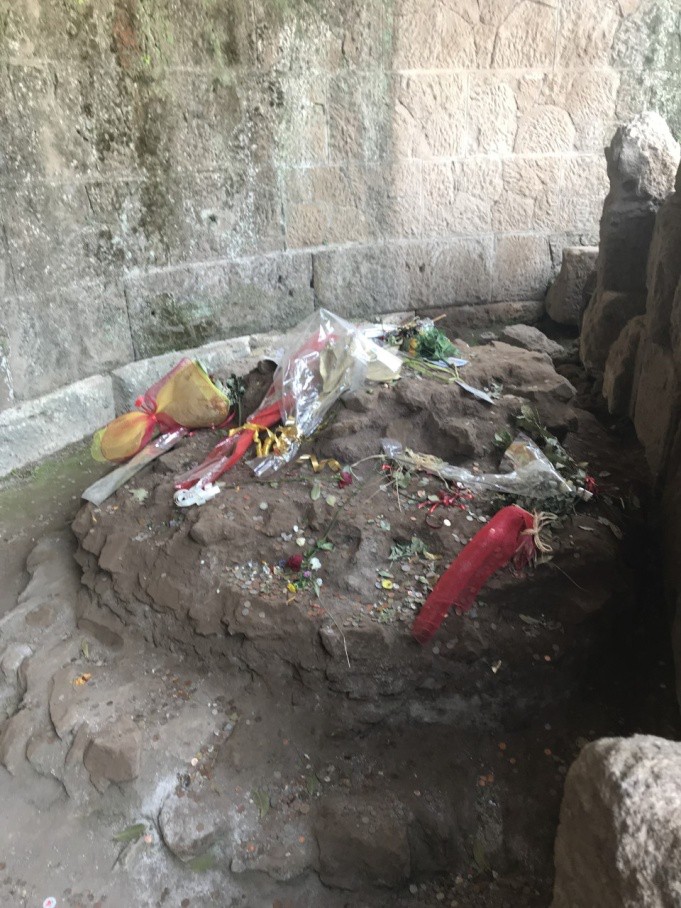 A photo of flowers sitting on an ancient tomb beside a stone block wall.