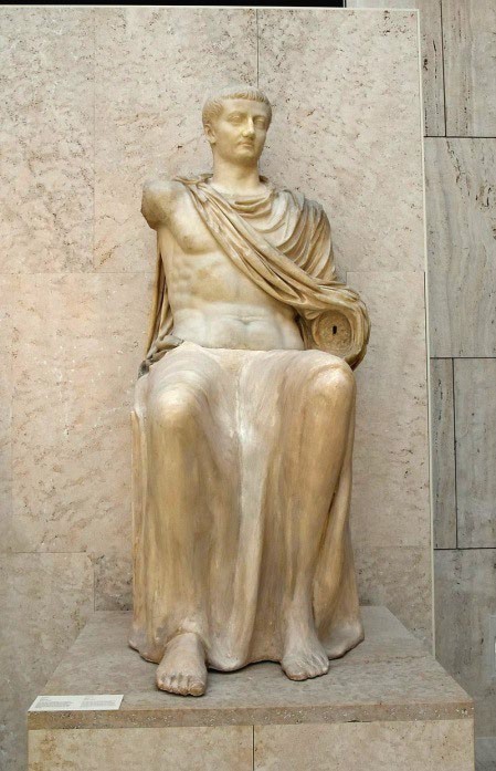 A seated, idealized man in a toga that reveals a well-developed torso carved from marble. Although his arms are now missing, it appears as though he was raising his right hand and rested the other on his knee.