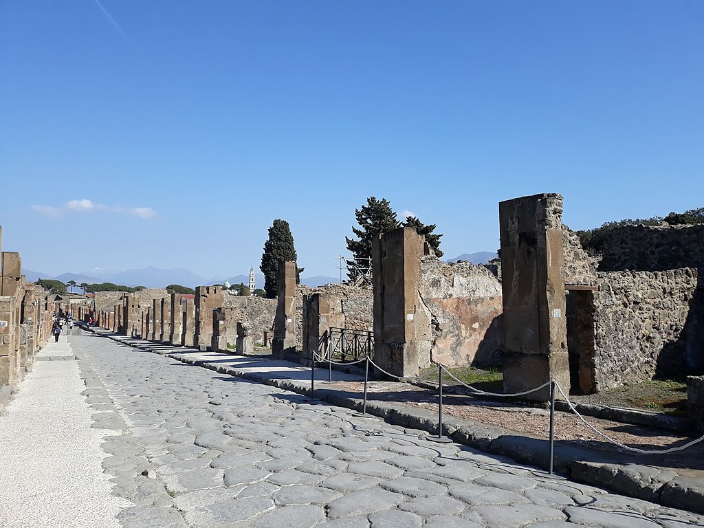 A street covered in large cobblestones with ruins on either side.
