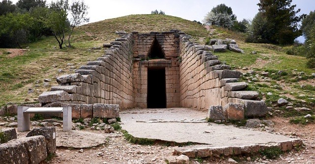 A stone walled entrance to a tomb. The post and lintel construction of the doorway is topped with a pointed arch.