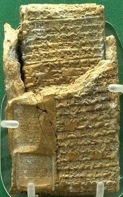 A clay tablet incised with cuneiform writing and partially enclosed in a clay case.