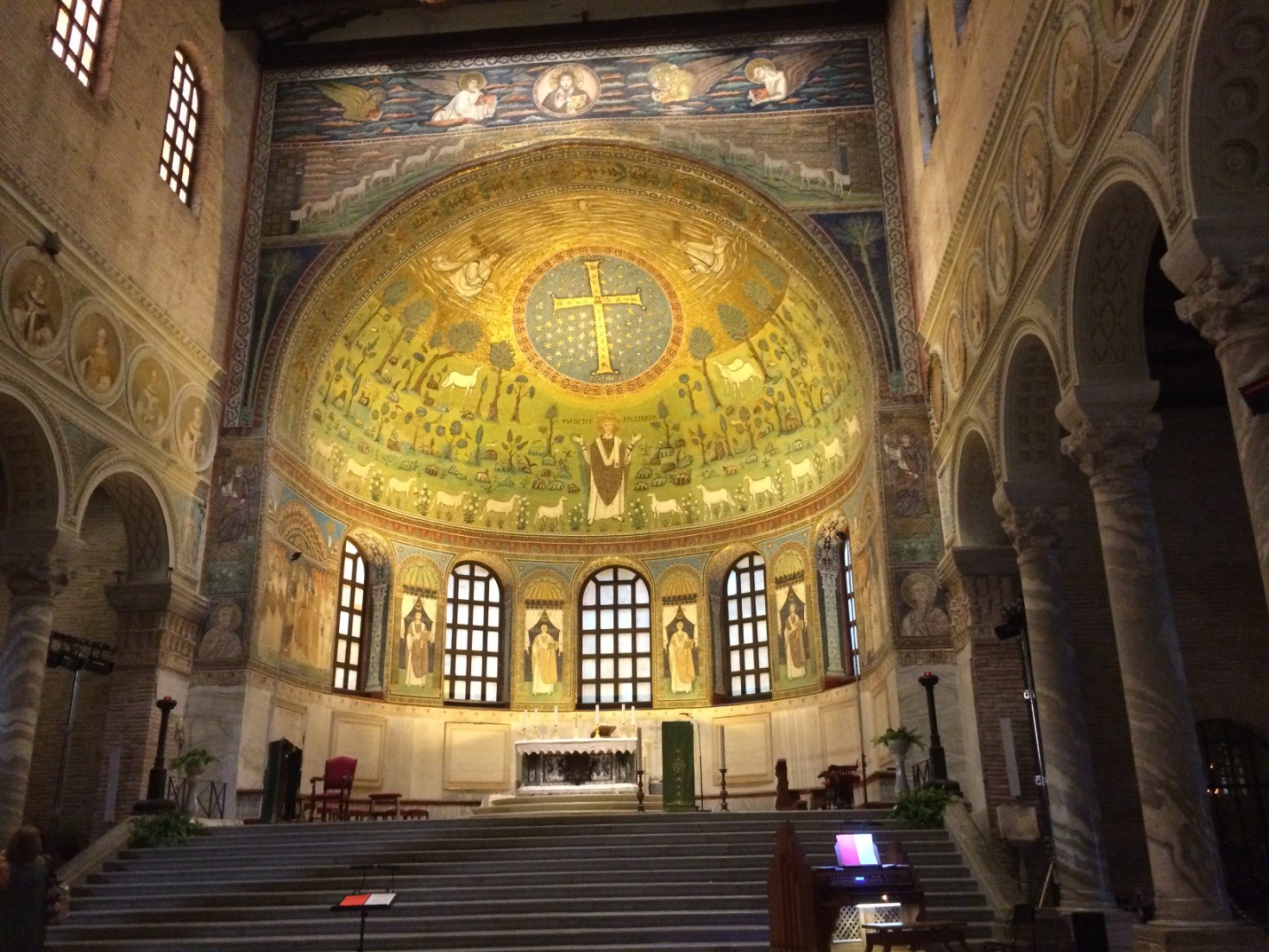 A view of the sanctuary revealing the mosaic poof Apollinare, the cross in the medallion and the image of Christ and the four apostles above it all.