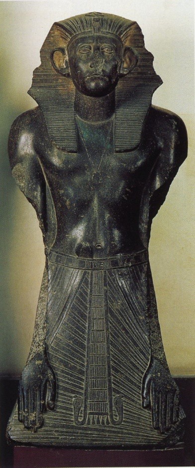 A fully frontal black granite statue depicting the upper half of the body of Sesostris III at prayer.