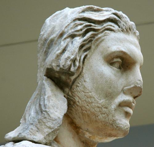 The head of a sculpture of an expressionless, bearded young man.