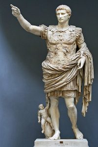 A sculpted, idealized man with his right hand raised, dressed in Roman battle gear. Cupid rides a dolphin at his feet.