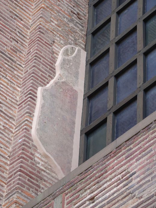 Remnants of plaster beside a window in a brick building.