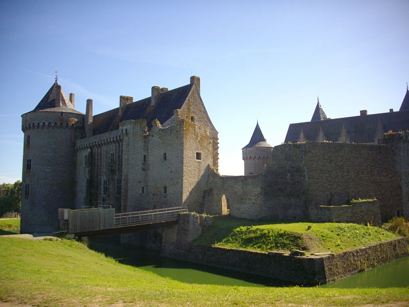 A distant view of the castle that includes a tower and the moat.