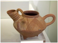A pot with three handles and a spout. It also has three knobs that hold it off the surface it sits on.