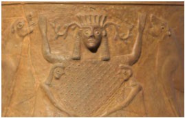 A bas-relief carving of a woman holding her arms up. She is flanked by a lion on each side.