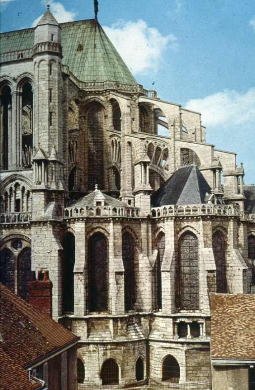 Large, curved buttresses soar above the lower cathedral roofs, supporting the nave.