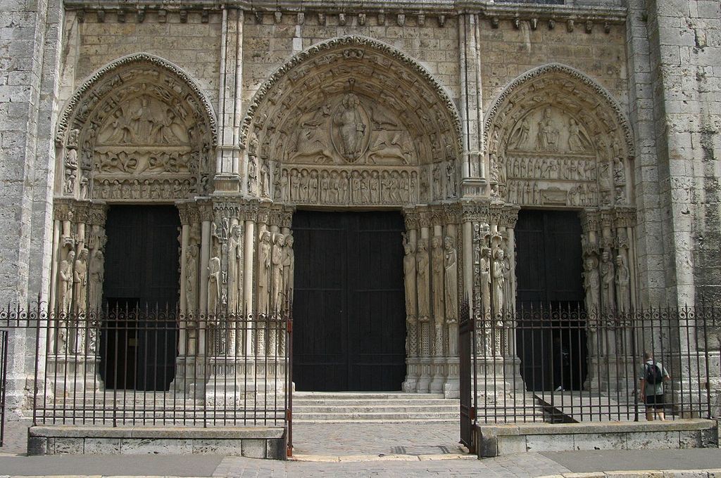 Three doors of the west portal. Each has carved figures on pillars and a tympanum with a story carved into it. Steps lead to the doors. Refer to the text for details.