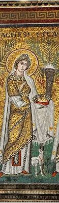 A woman with a halo dressed in gold and white and holding a crown. A sheep stands at her feet and palm trees are behind her.
