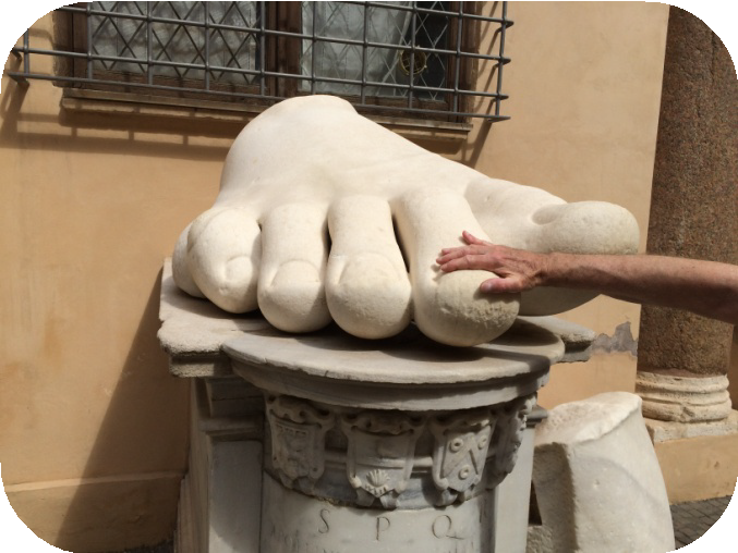 A person dwarfed by the foot of the Constantine colossus.