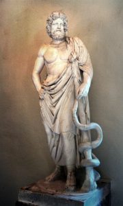 A marble statue of a bearded man with an idealized torso and a robe that covers his bottom half. He leans on a staff that has a snake curled around it and stands in a contrapposto pose with his right hand resting on his hip.