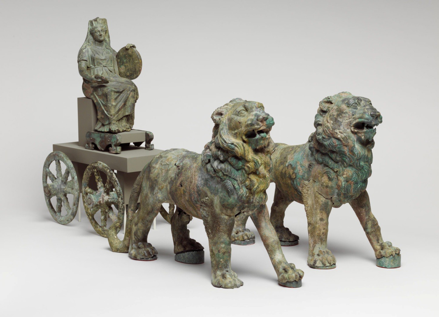 A bronze statue of a cart driven by a woman and pulled by stylized lions.
