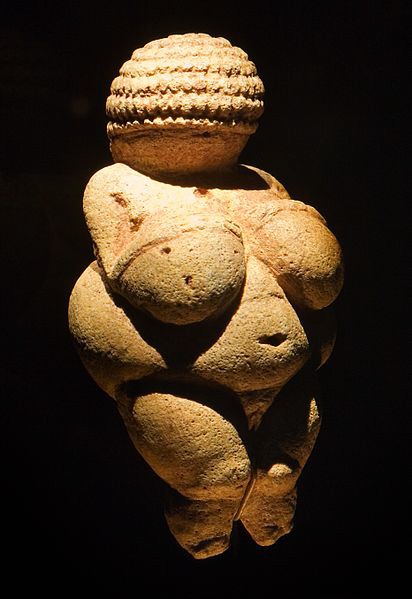 A small stone carving of a woman with no feet or face.