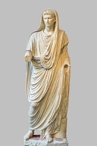 A sculpture of an idealized man in a long robe that covers his head.