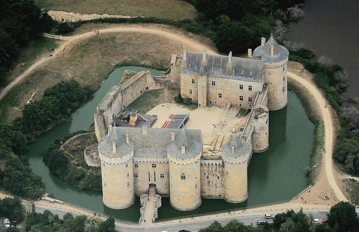 An aerial view reveals a moat, four towers and a bridge and courtyard.