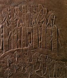 A bas relief shows men tearing down the city walls while others take goods out of the city gates.