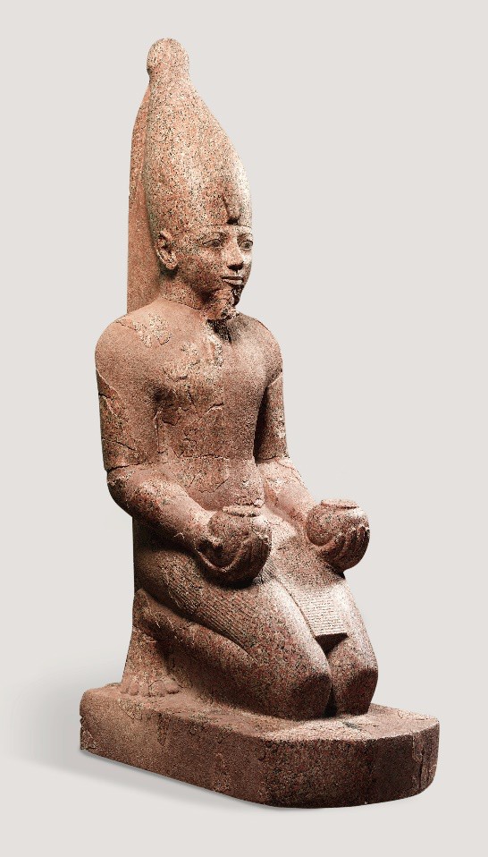 A carving of Hatshepsut as a male in prayer. She holds an orb in each hand.