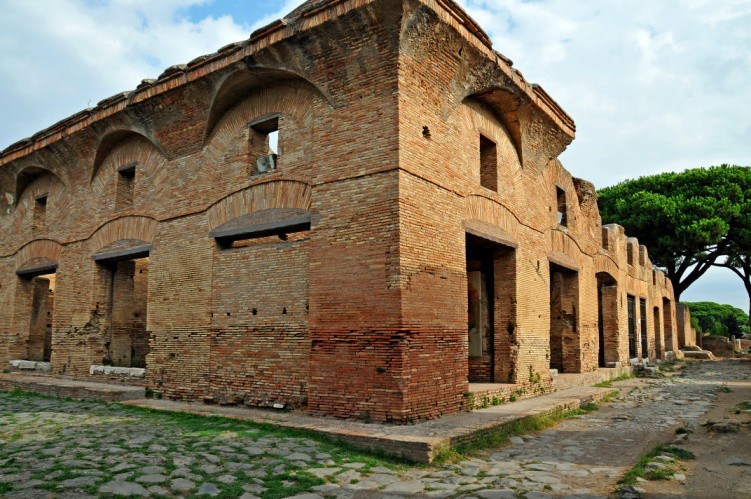 A stone block building with arches built into the walls to support an upper story with rectangular windows.
