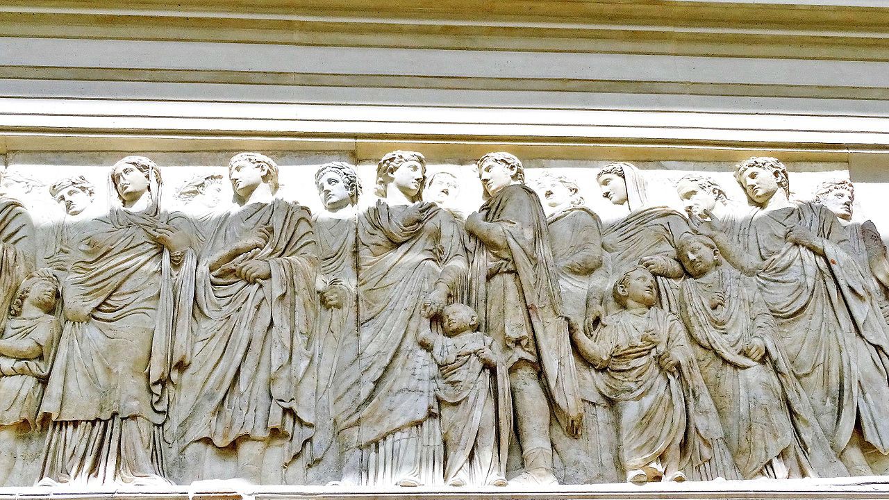 A close-up of a carving of Roman men, women and children in a scattered line.