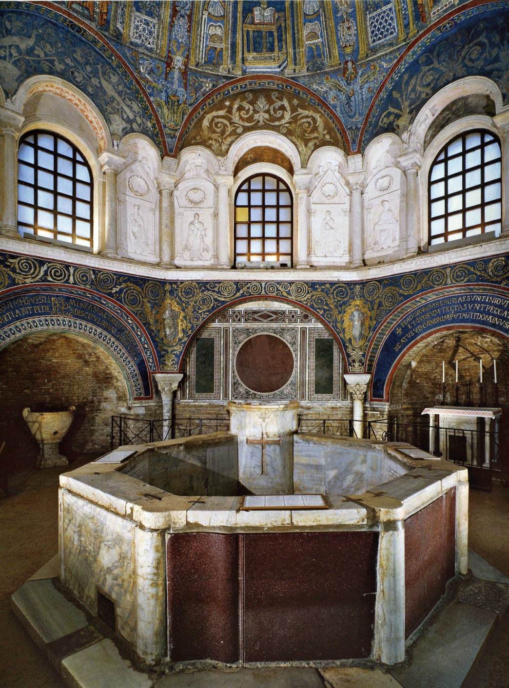 The Baptismal font and the elaborate mosaic work behind it, broken up by windows.