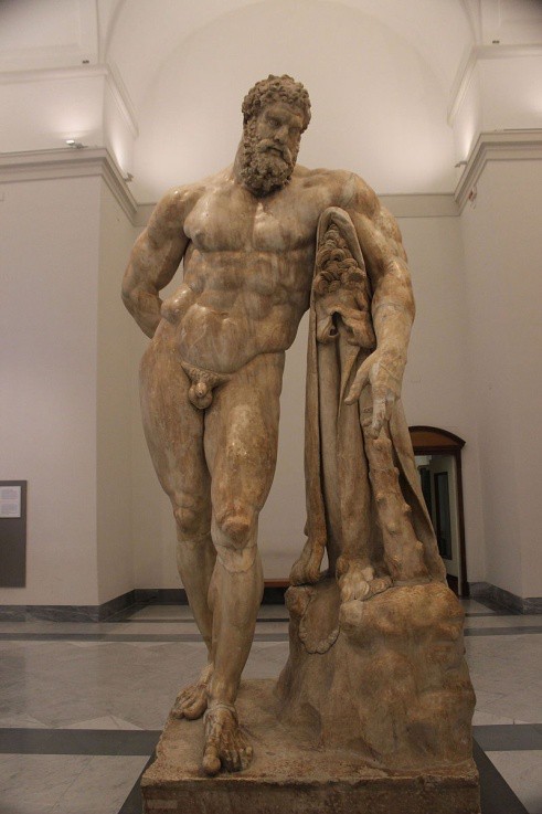 An overly muscular bearded man leaning, as if he is tired, against an object covered by a lion’s skin with his club also leaning against it.