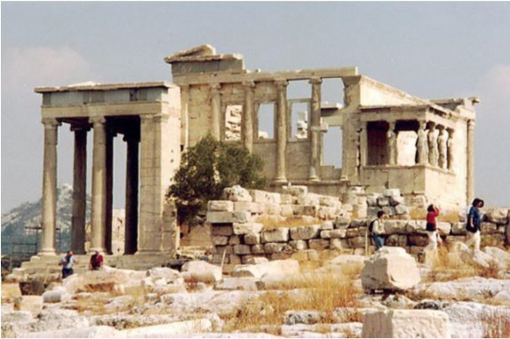 A photo of the Erectheum. The temple sits on three different levels and is in the Ionic style.