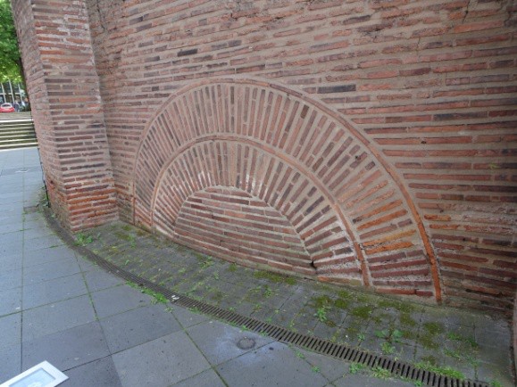 An arch filled with brickwork reveals where the heating system originally was.