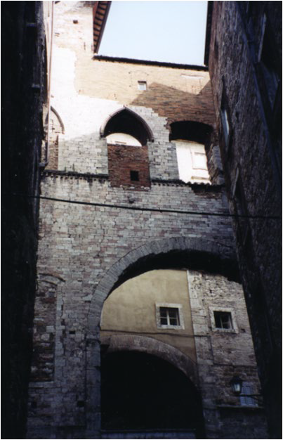 A photo of a reconstruction of the Temple of Veii. An arch supports an upper wall.