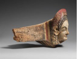 An Etruscan roof tile decorated by a smiling face, resembling the kouros in image 4.63.