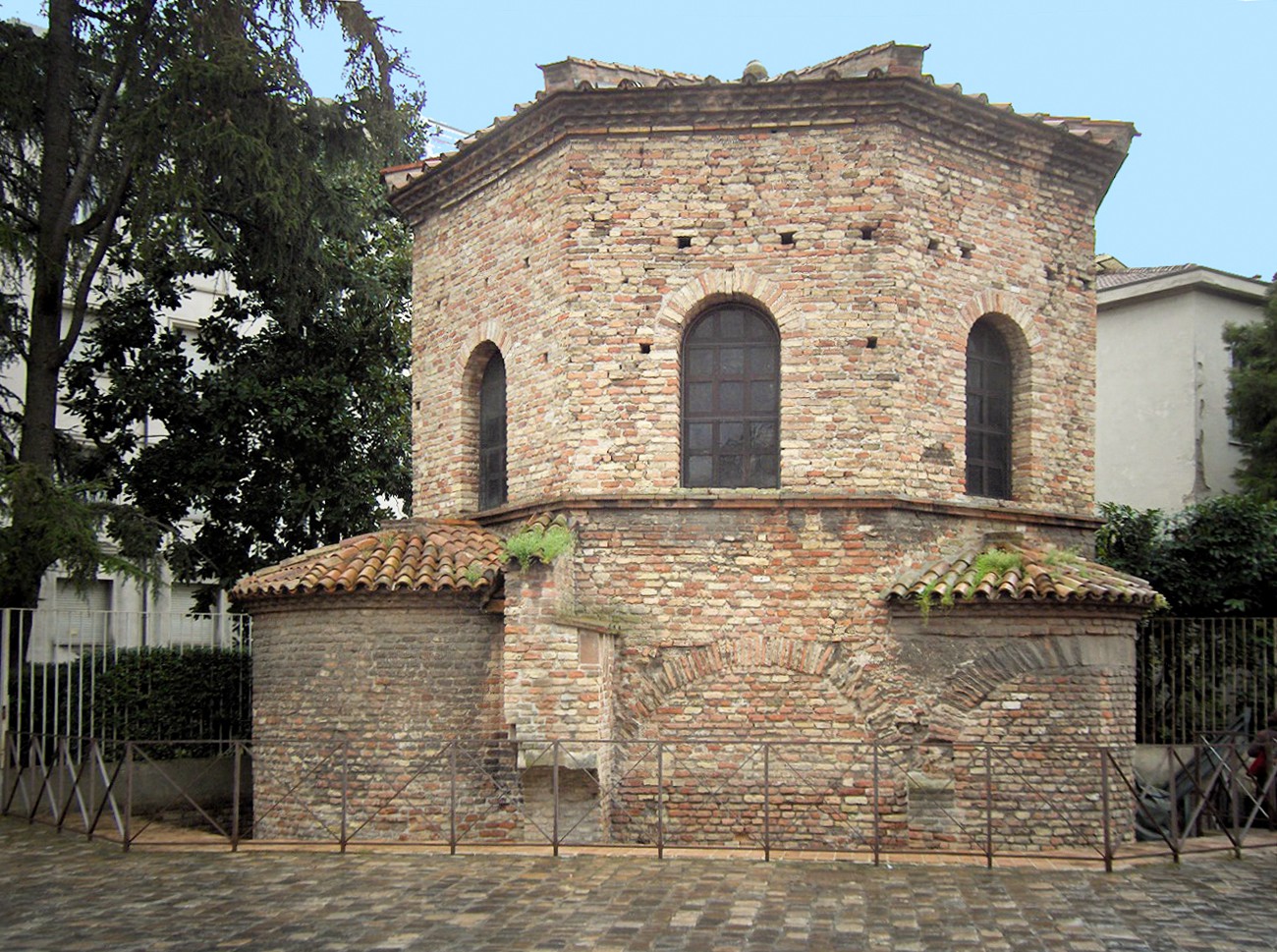 Exterior of a two-story high octagonal brick building with arched windows on the second story. There are two visible apses on the first floor.
