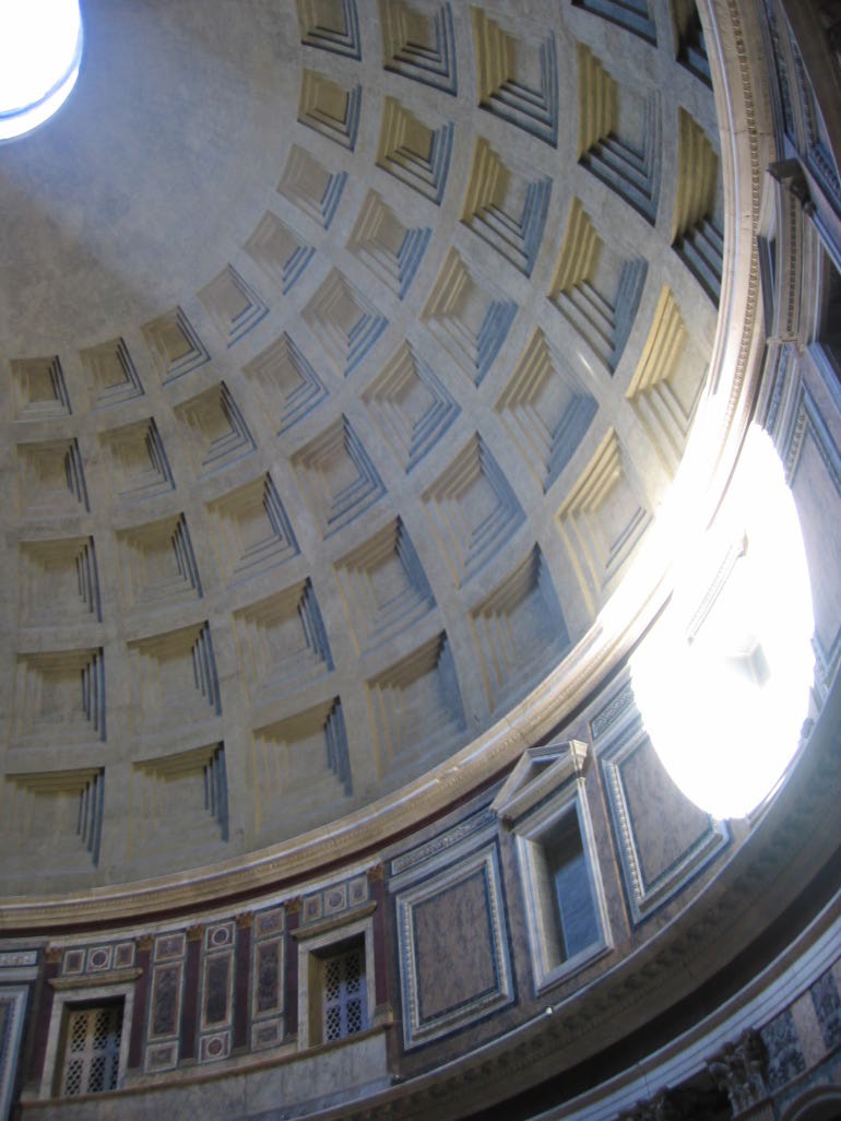 A partial view of the oculus as light shines through it and strikes a niche on the wall.
