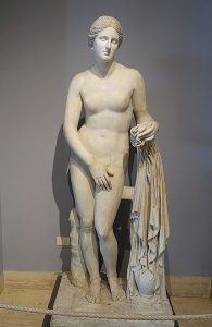 Sculpture of a nude woman supported by the cloth she holds in one hand. She stands with one hip higher than the other.
