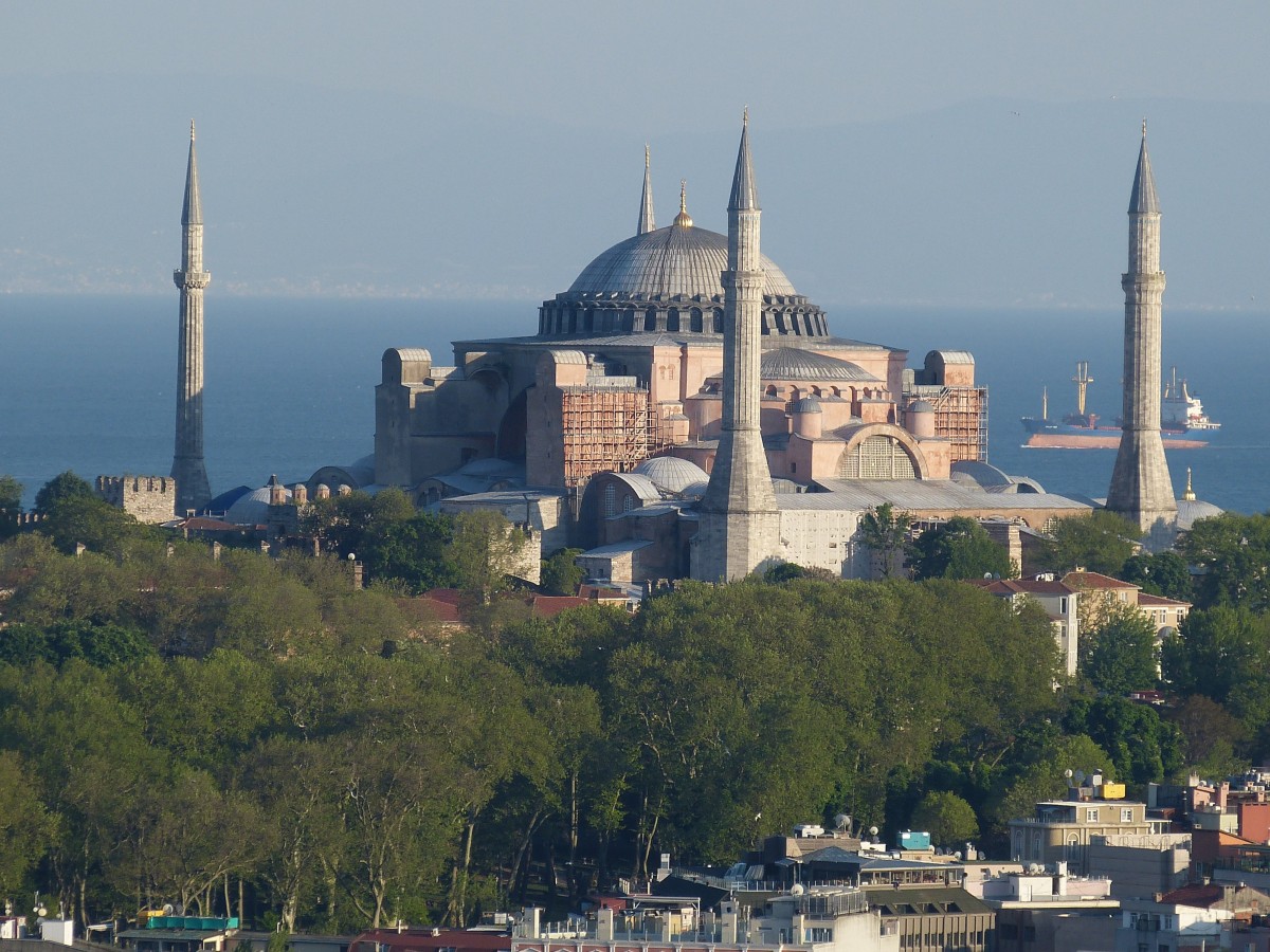 Huge building with a central dome and minarets on four corners. The sea is in the background.
