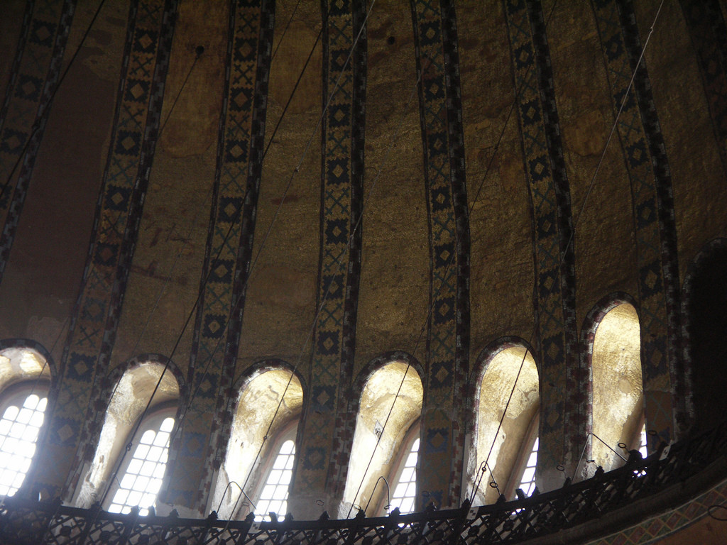 The closely spaced windows that surround the base of the dome are much wider at the top than at the bottom. This allows for the dome shape as well as providing more rea to cover with reflective gold mosaics.