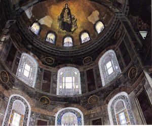 The mosaic of Mary and her child seen on the surface of a semi-dome. Rows of non-representational stained-glass windows are below it.