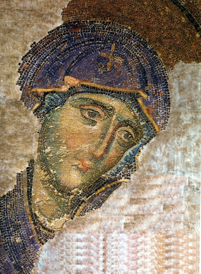 A close-up of Mary’s head showing d=sorrowful eyes and a cross on her blue headdress.