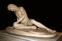 A statue of a man dying from a battle wound. He leans on one arm and gazes into the reflection of his face on his sword.