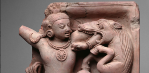 A man shoving his arm into the mouth of an animal that looks like a cross between a horse and a dragon.