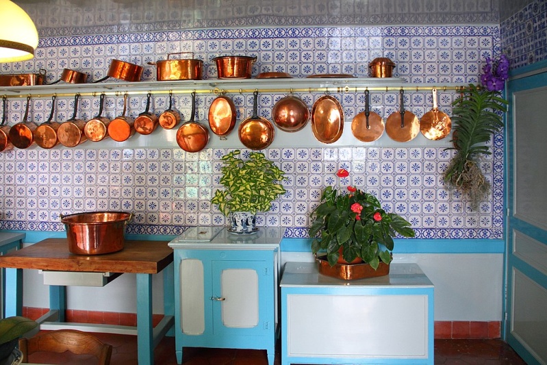 Photograph of Monet’s kitchen in Giverny, near Paris. Blue and white kitchen with copper pots hanging along back wall