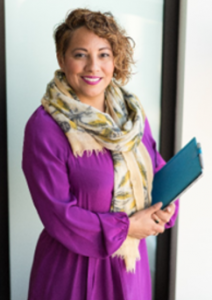 Professor Escobar, a Hispanic woman with short curly hair holding books