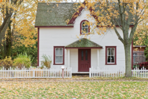 A white house with a white fence Description automatically generated